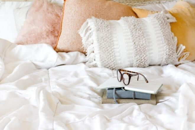 notebook and glasses on a bed
